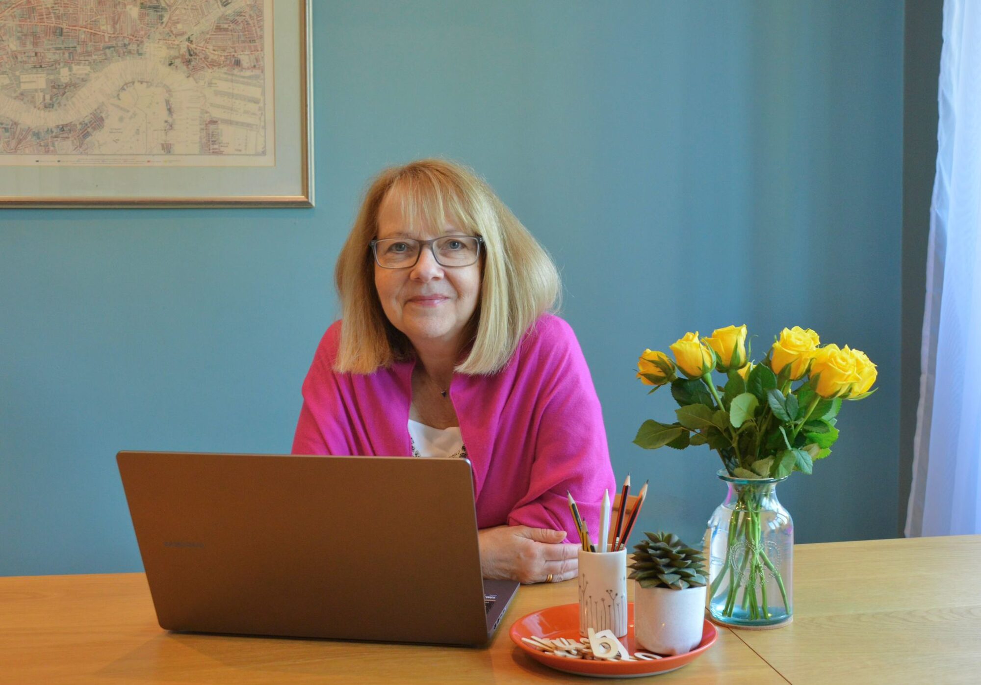 Christine at her desk with her laptop and fresh flowers